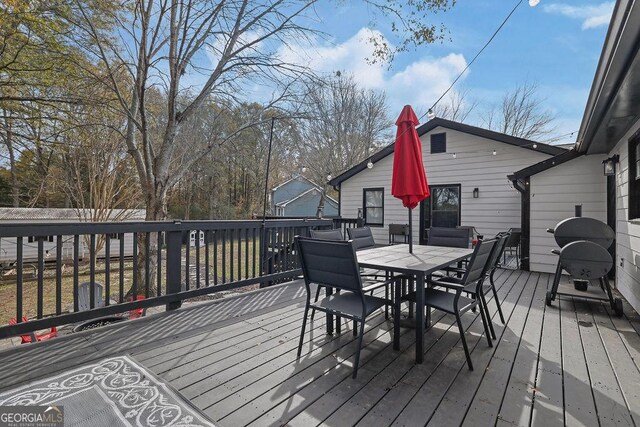 wooden terrace with a trampoline and a grill