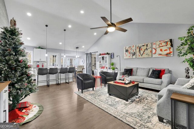 living room featuring ceiling fan, dark wood-type flooring, and lofted ceiling