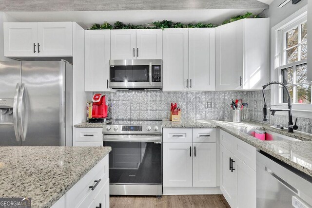 kitchen featuring a barn door, appliances with stainless steel finishes, a center island, white cabinetry, and lofted ceiling