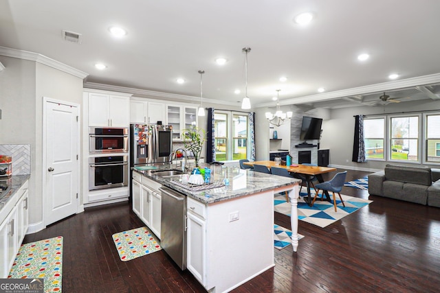 kitchen featuring white cabinetry, sink, stainless steel appliances, a center island with sink, and ceiling fan with notable chandelier