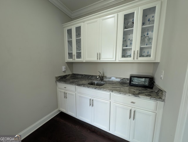 bar featuring stone counters, white cabinetry, sink, dark hardwood / wood-style flooring, and ornamental molding