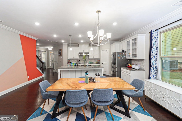 dining area with a notable chandelier, dark hardwood / wood-style floors, sink, and crown molding