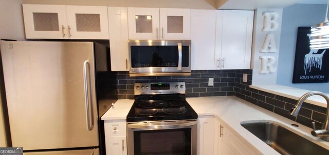 kitchen with tasteful backsplash, sink, white cabinets, and stainless steel appliances