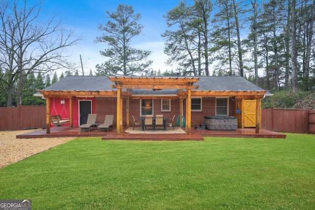 rear view of property featuring a pergola, a hot tub, a lawn, and a wooden deck