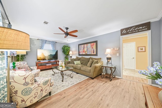 living room featuring wood-type flooring, ceiling fan, and crown molding