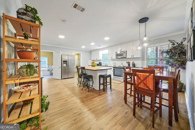 dining room featuring light hardwood / wood-style floors, ornamental molding, and sink