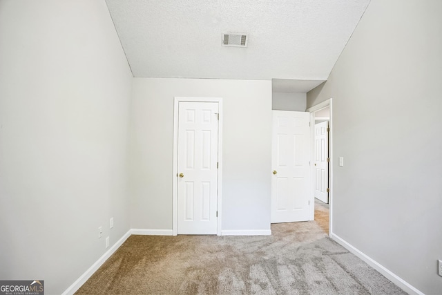 unfurnished bedroom featuring light carpet and a textured ceiling