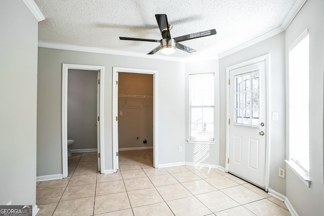 foyer featuring a textured ceiling, ceiling fan, light tile patterned floors, and crown molding