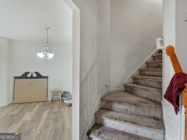 stairway featuring wood-type flooring and a notable chandelier