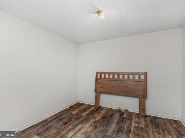 unfurnished room with a textured ceiling and dark hardwood / wood-style flooring