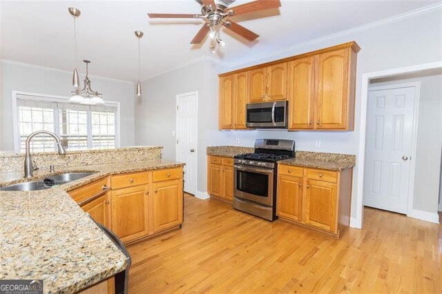 kitchen with appliances with stainless steel finishes, ornamental molding, ceiling fan, sink, and hanging light fixtures