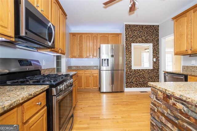 kitchen featuring light stone countertops, crown molding, appliances with stainless steel finishes, and light hardwood / wood-style flooring