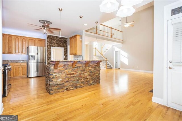 kitchen featuring range, stainless steel refrigerator with ice dispenser, light hardwood / wood-style flooring, ceiling fan, and kitchen peninsula