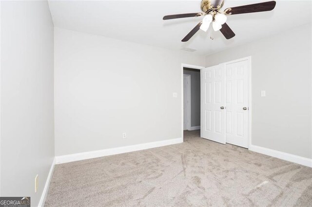 spare room featuring light carpet and ceiling fan