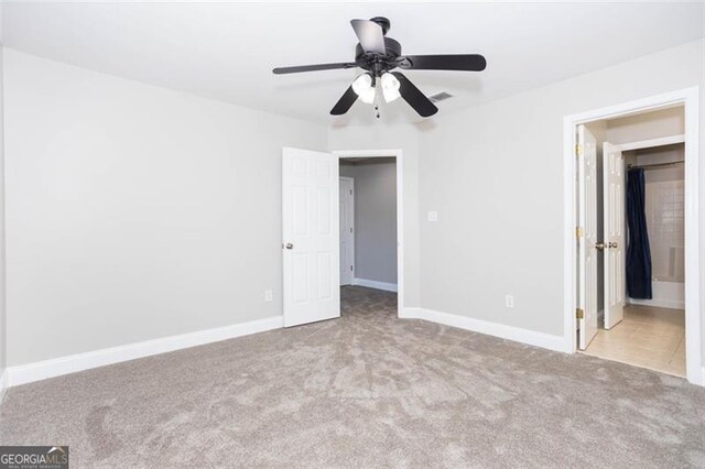 unfurnished bedroom featuring light carpet, ensuite bathroom, and ceiling fan