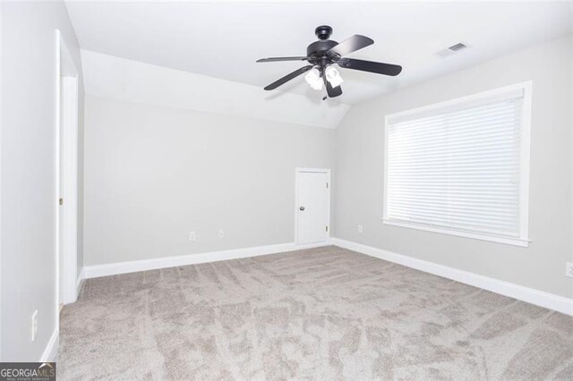 empty room with ceiling fan, lofted ceiling, and light carpet