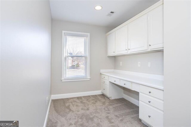 unfurnished office featuring light colored carpet and built in desk