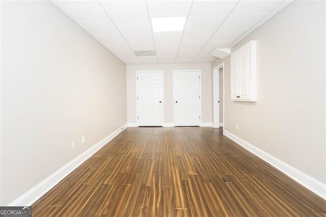 unfurnished room featuring a drop ceiling and dark wood-type flooring