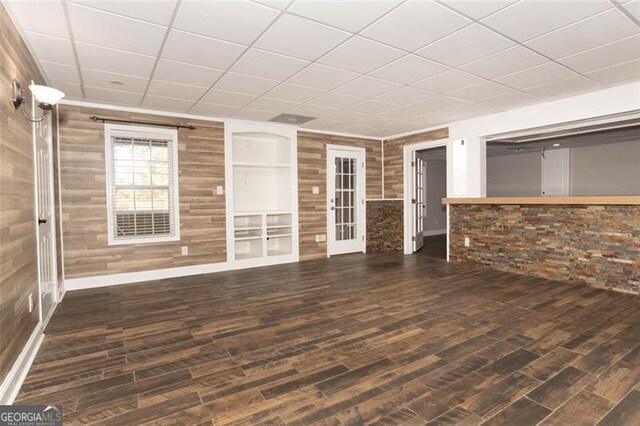 unfurnished living room with wood walls and dark hardwood / wood-style flooring