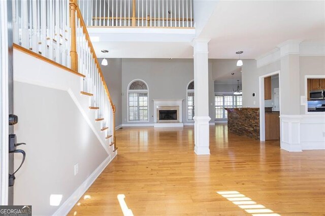 unfurnished living room with decorative columns, plenty of natural light, wood-type flooring, and a high ceiling