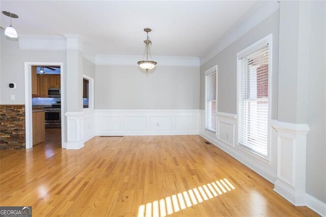 unfurnished dining area with ceiling fan, a healthy amount of sunlight, crown molding, and light hardwood / wood-style flooring