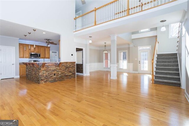 unfurnished living room with a towering ceiling, light hardwood / wood-style flooring, and a wealth of natural light