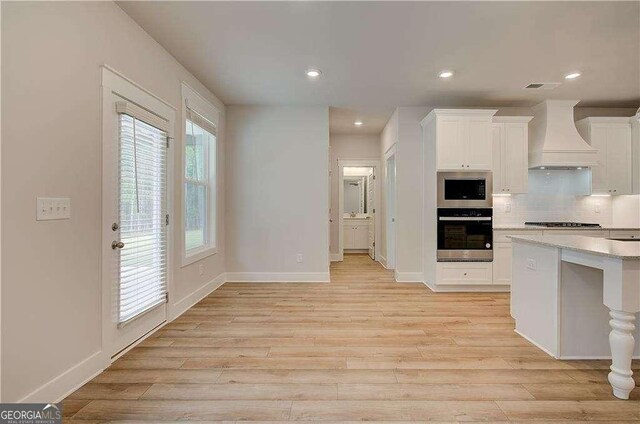 kitchen featuring white cabinets, ceiling fan, light hardwood / wood-style flooring, and an island with sink