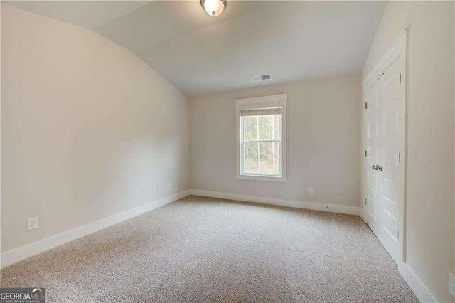 carpeted empty room with vaulted ceiling