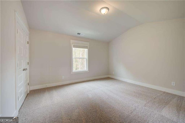 carpeted empty room with lofted ceiling