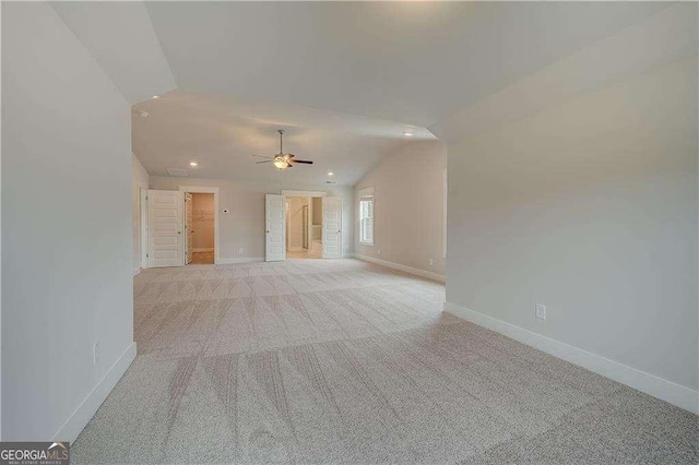 unfurnished living room with ceiling fan, light colored carpet, and lofted ceiling