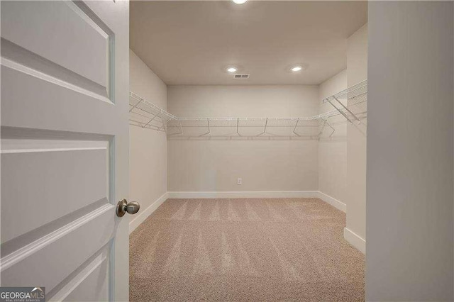 walk in closet featuring light colored carpet