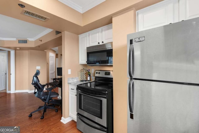 kitchen with ornamental molding, white cabinets, stainless steel appliances, and light wood-type flooring