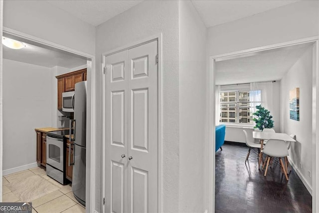 kitchen featuring a textured ceiling, light tile patterned flooring, and stainless steel appliances