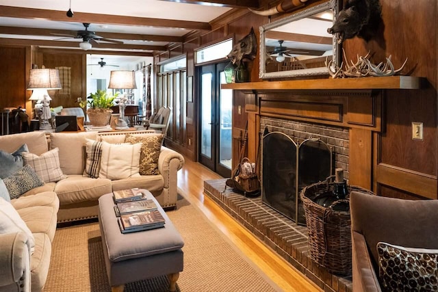 living room featuring beamed ceiling, a fireplace, wooden walls, and hardwood / wood-style floors