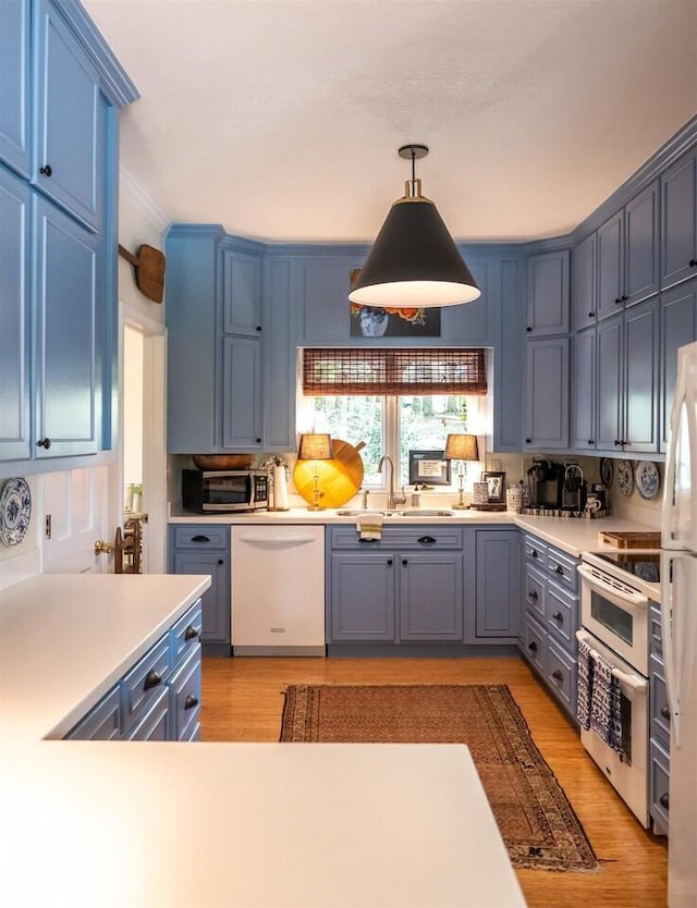 kitchen featuring sink, blue cabinetry, pendant lighting, dishwasher, and range