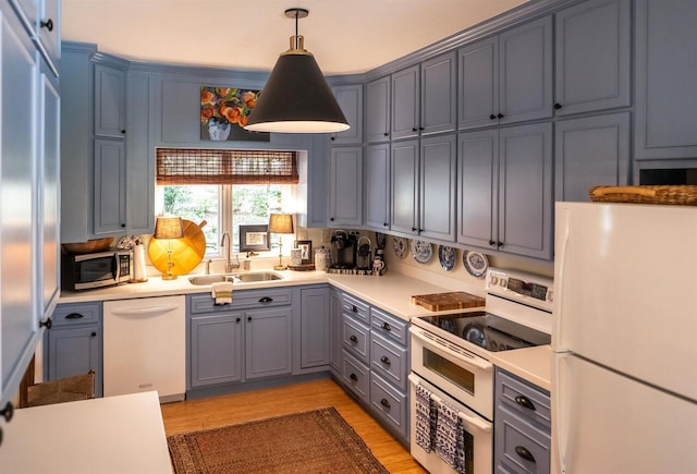 kitchen featuring decorative light fixtures, white appliances, sink, and light hardwood / wood-style flooring