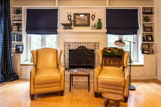 living area with a tile fireplace and light wood-type flooring