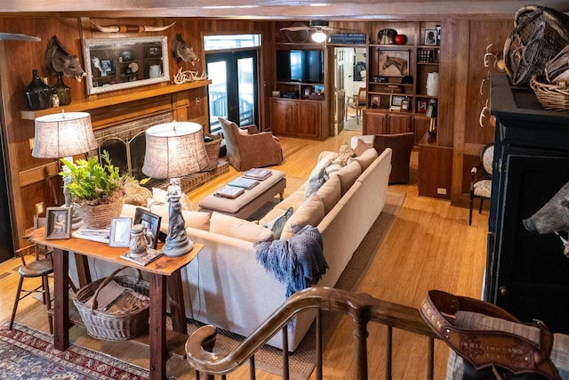 living room with hardwood / wood-style floors, french doors, and wooden walls