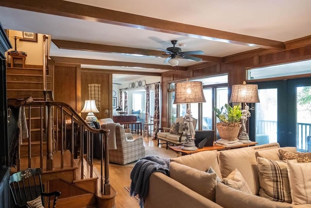 living room with beam ceiling, a healthy amount of sunlight, wooden walls, and french doors