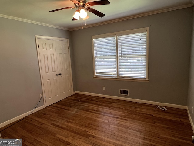 unfurnished bedroom featuring dark hardwood / wood-style flooring, ceiling fan, a closet, and ornamental molding