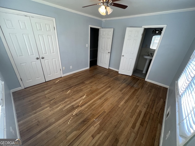 unfurnished bedroom featuring ceiling fan, ensuite bath, multiple windows, and a closet