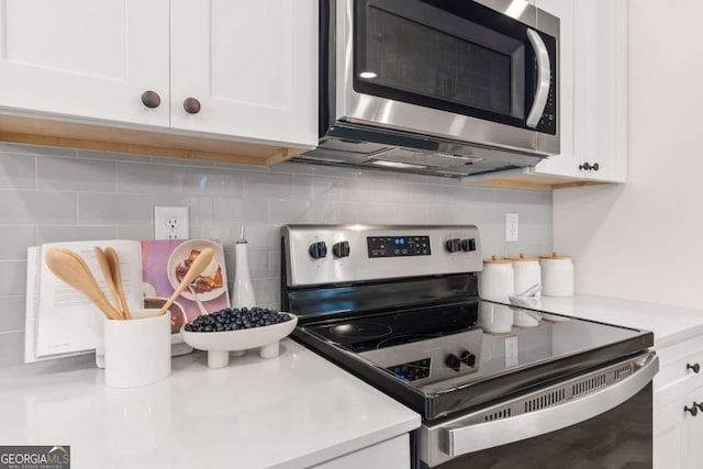 kitchen with white cabinets, appliances with stainless steel finishes, and tasteful backsplash