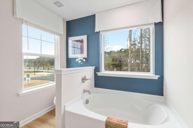 bathroom with hardwood / wood-style flooring, toilet, and a tub