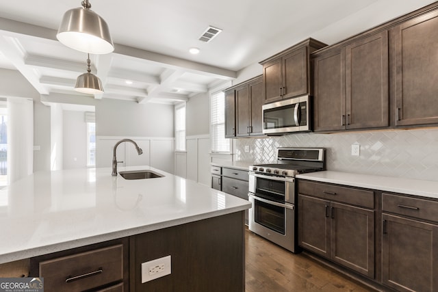 kitchen with coffered ceiling, sink, hanging light fixtures, beam ceiling, and stainless steel appliances