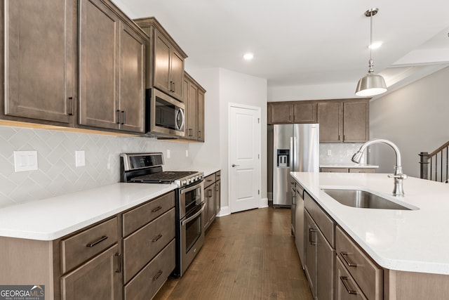 kitchen with sink, stainless steel appliances, dark hardwood / wood-style flooring, pendant lighting, and decorative backsplash