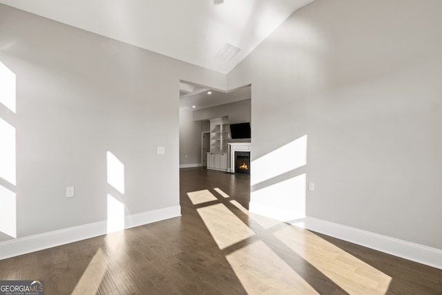 empty room featuring high vaulted ceiling and dark wood-type flooring