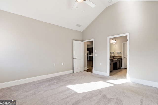 unfurnished bedroom with light carpet, ceiling fan, sink, high vaulted ceiling, and connected bathroom