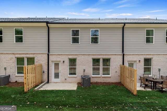 rear view of property featuring a lawn, a patio area, and central air condition unit