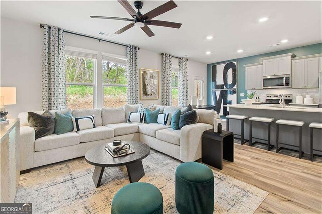 living room with light hardwood / wood-style flooring and ceiling fan