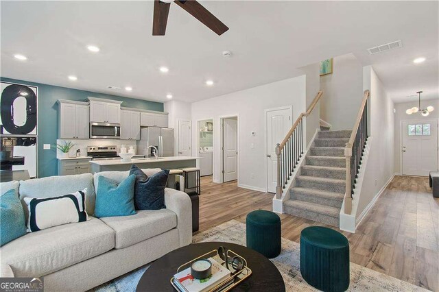 living room with ceiling fan, light hardwood / wood-style floors, and washer / dryer